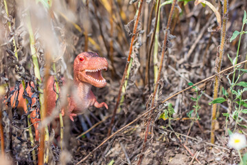 Toy dinosaur in the thicket imitates the natural environment. Toy for children.