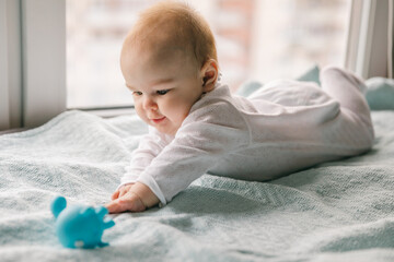 A three-month-old baby reaches for a toy. Psychomotor development and the first toys for a child