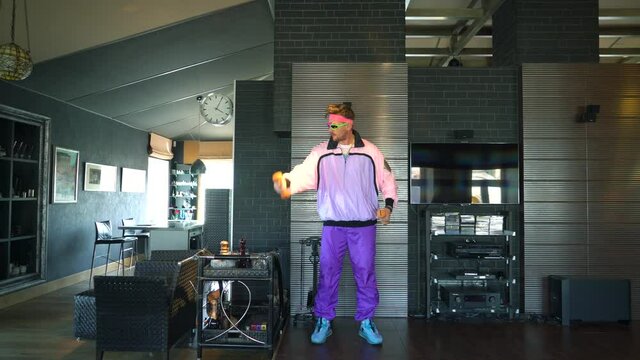 An unusual sports freak in a stylish bright suit of the 80s is engaged in fitness at home, a handsome cheerful gay guy entertains himself at home on self-isolation, a meme for social networks.