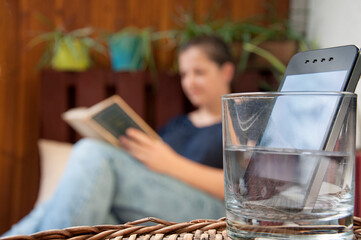 digital detox_smartphone_glass with water_woman reading_by jziprian