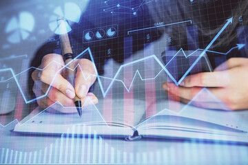 Double exposure of businesswoman hands typing on computer and forex graph hologram drawing. Financial analysis concept.