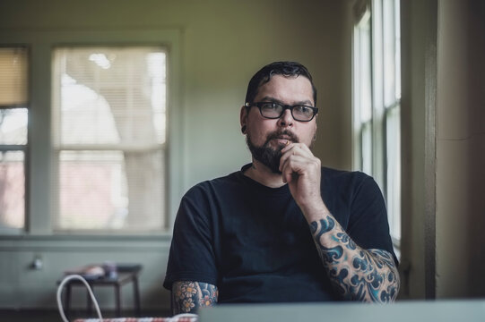 A handsome tattoo'd man in window light