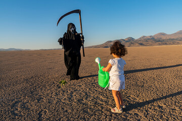 horror grim reaper holding is holding a clock in one hand and a scythe in the other. A green plant...