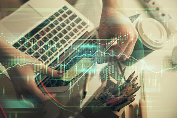Double exposure of businesswoman hands typing on computer and financial graph hologram drawing. Stock market analysis concept.