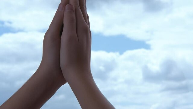 Namaste position. Hands of a girl in namaste on a background of blue sky.