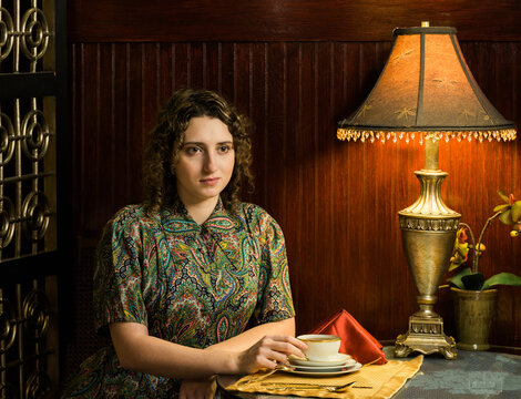 A 1950s period portait of a young sophisticated woman at a high tea cafe