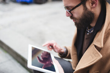 Young man using his digital tablet outdoors