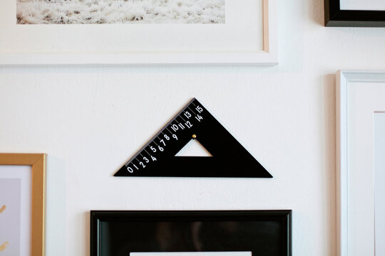 Square ruler used as decor object hanging close to paintings on wall