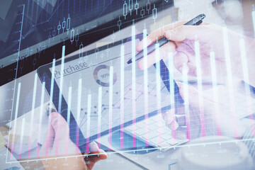 Double exposure of man's hands holding and using a phone and financial chart drawing. Market analysis concept.