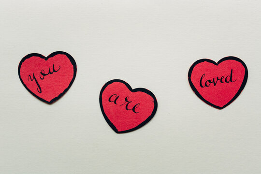 You are loved"" written on red paper hearts