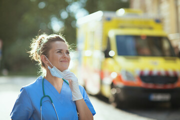 happy medical doctor woman breathing outside near ambulance