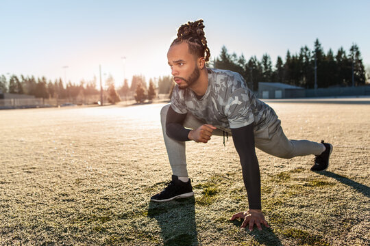 African American athlete stretching on the football field