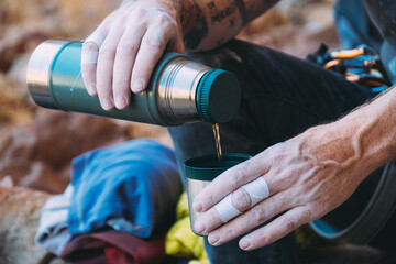 Climbers hands pouring tea/coffee from a flask into a cup