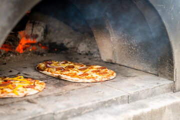 cooking pizza in an outdoor wood fired pizza oven