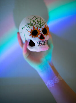Painted sugar skull being help up against a prism