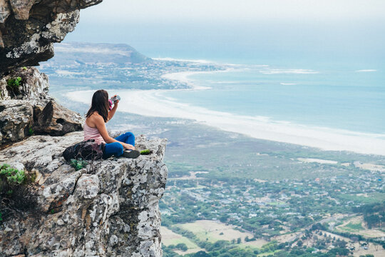 Hiker sitting on a rocky mountain summit enjoying a scenic view
