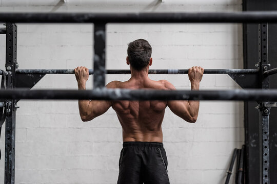 Man doing pull-ups in a gym. view from behind