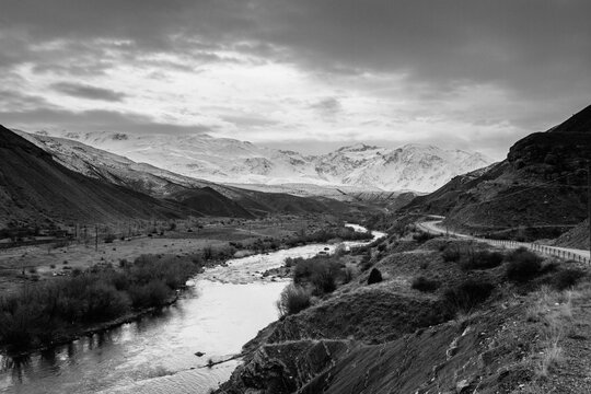 remote valley with a river and a road leading to snowcovered mountain range