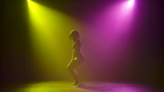 Woman dancing latin music. Bachata, merengue, salsa. Shot in a dark studio with neon lights in the background.