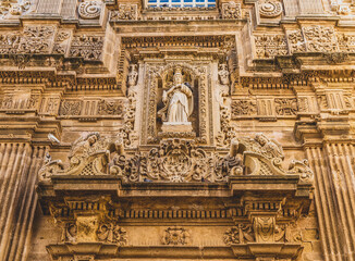 Fototapeta na wymiar Details of the façade of the Baroque cathedral of Sant'Agata built in the 17th century, Gallipoli, Salento, Puglia region, Italy. Facade decorated in carparo, a local limestone.