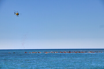 Helicopter dropping flowers on distant surfers during a celebration of life ceremony on Maui.