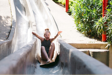 Fun loving girl sliding down cement slides.