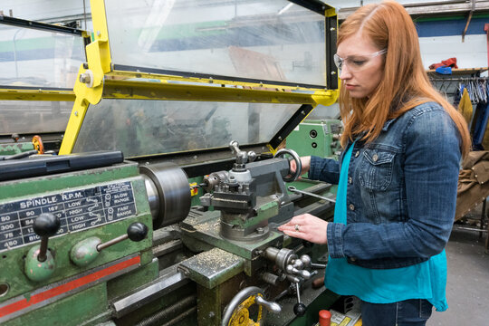 Female company executive tries out lathe in machine shop - Powered by Adobe