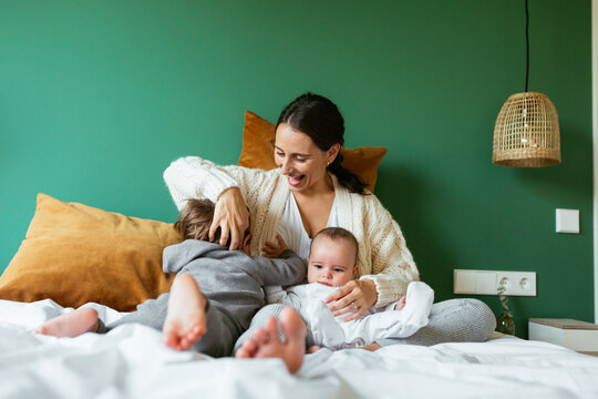 Excited mother playing with kids on bed