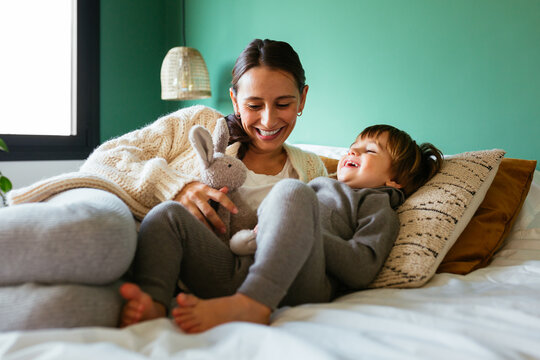 Cheerful mother playing with son on bed