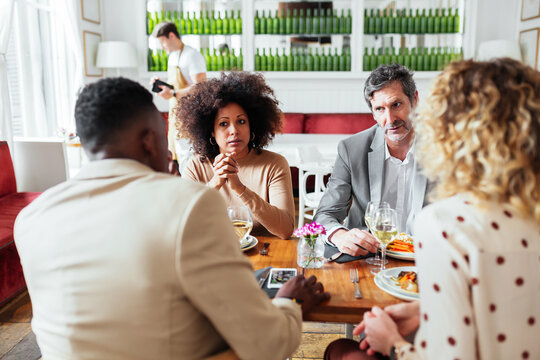 Diverse people talking during dinner in restaurant