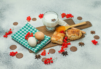 Pastries with flour, currants, milk, eggs, spices, cookies high angle view on concrete and cutting board background