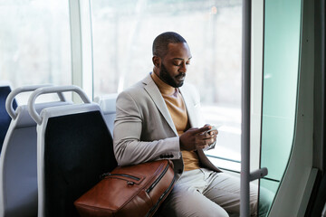 Stylish ethnic man using smartphone in bus