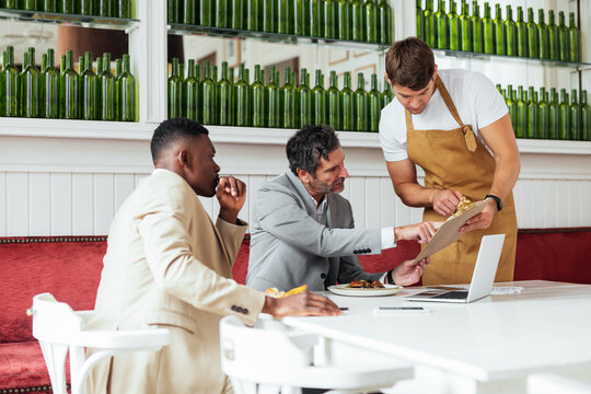 Multiracial businessmen making order in cafe