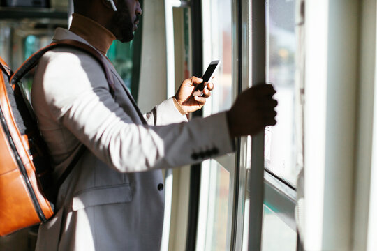 Crop black guy browsing smartphone and listening to music in bus