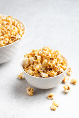 caramel popcorn in a white bowl with a big bowl in the background