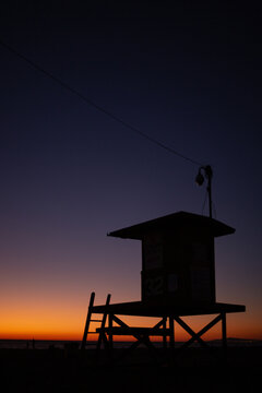 The sun sets behind a lifeguard tower.
