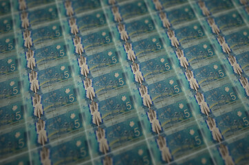 5 Canadian dollars bills printed in illegal money production conveyor. Collage of many fake bills....