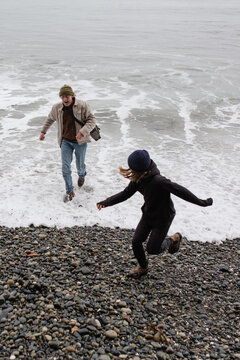 Fun grandpa playing with grandkids on rugged beach in winter.