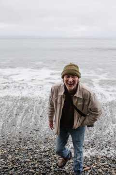 Laughing older man on the beach in winter.