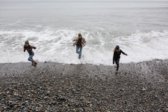Fun grandpa playing with grandkids on rugged beach in winter.