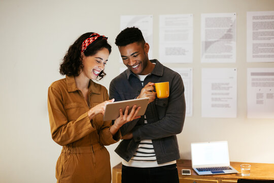 Cheerful diverse colleagues using tablet in office