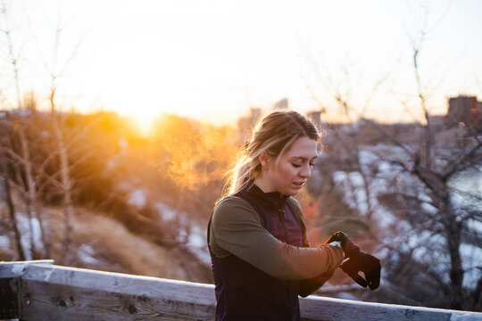Runner woman checking her watch on a cold, winter run.