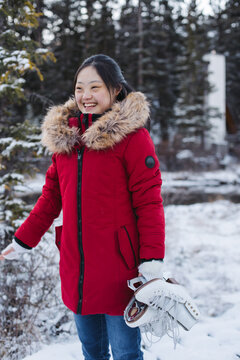 Young woman outside in winter wearing red coat and holding figur