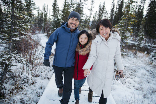 Parents and adult daughter walking together on winter path.