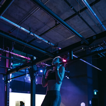Sweaty athlete woman training hard in dark, moody gym.