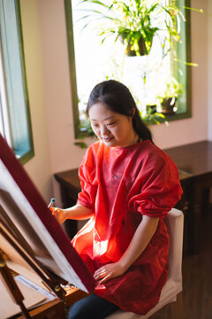 Young woman painting at home.