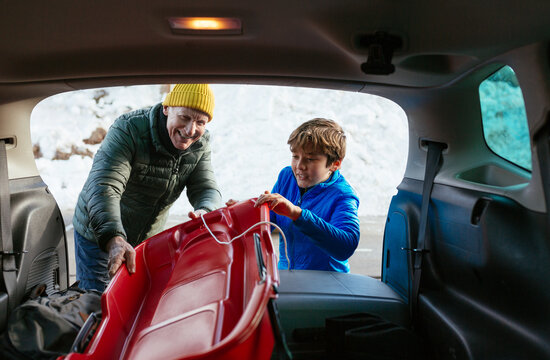 Grandfather and grandson taking sled from car