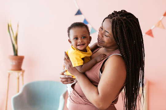 Happy black mother hugging baby at home