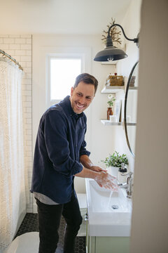 Man washing hands in bathroom at home.