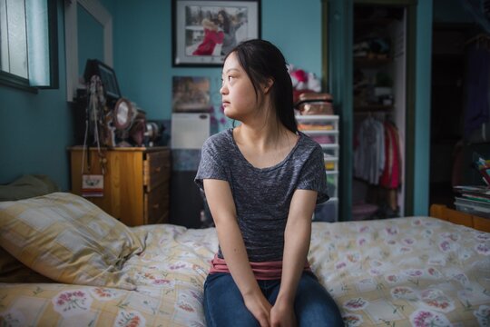 Young woman sitting in Bedroom looking out the window